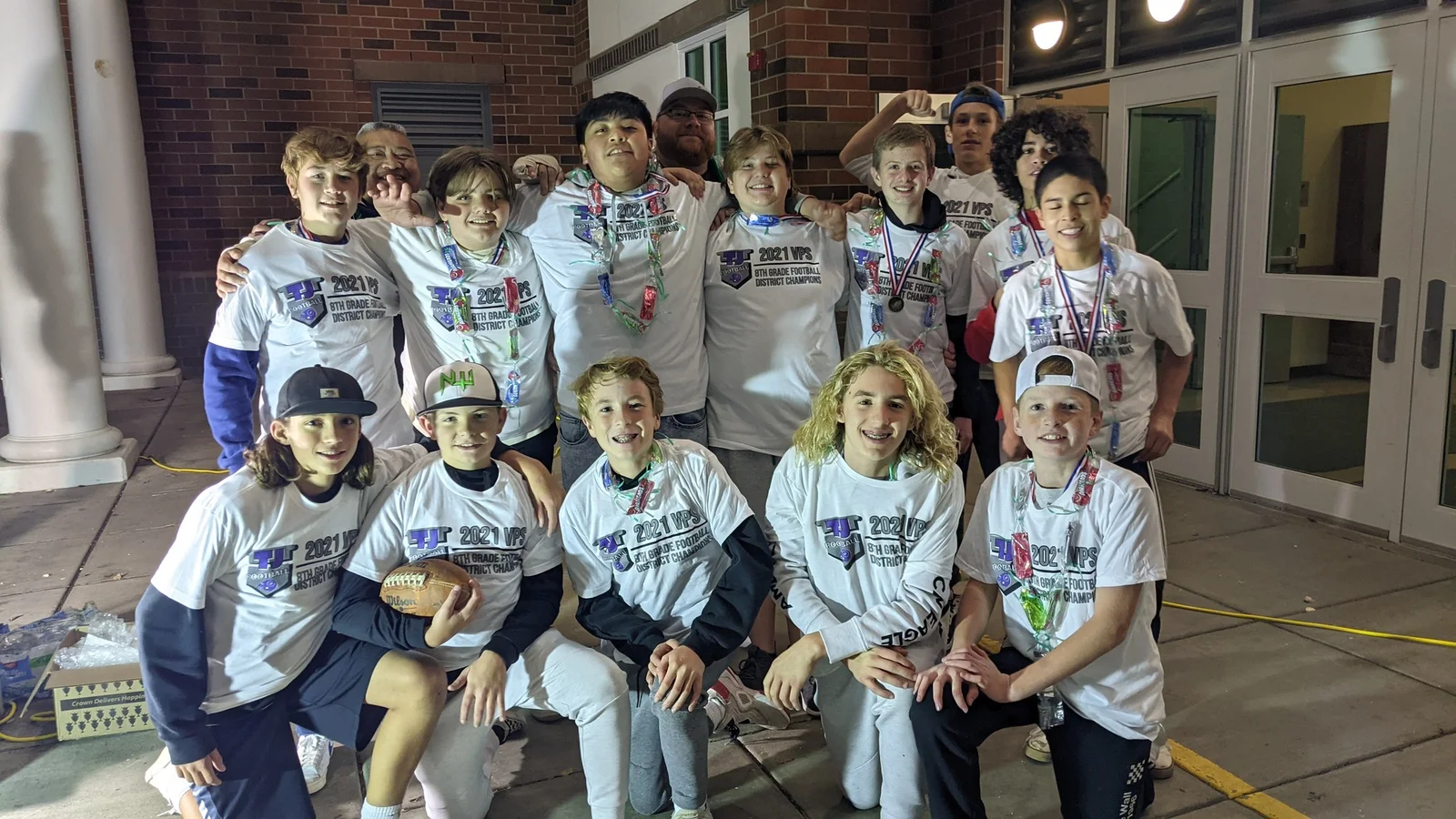 Youth sports team celebrating together with medals, wearing Left Coast Exteriors shirts
